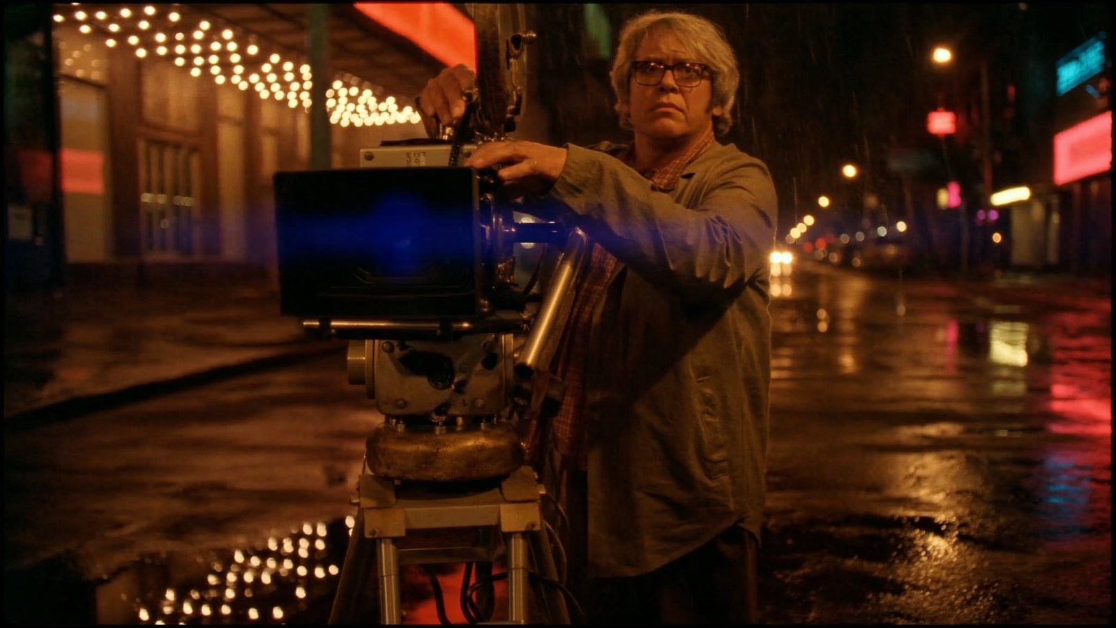 Cinematographer adjusting a cinema camera on a rainy night street